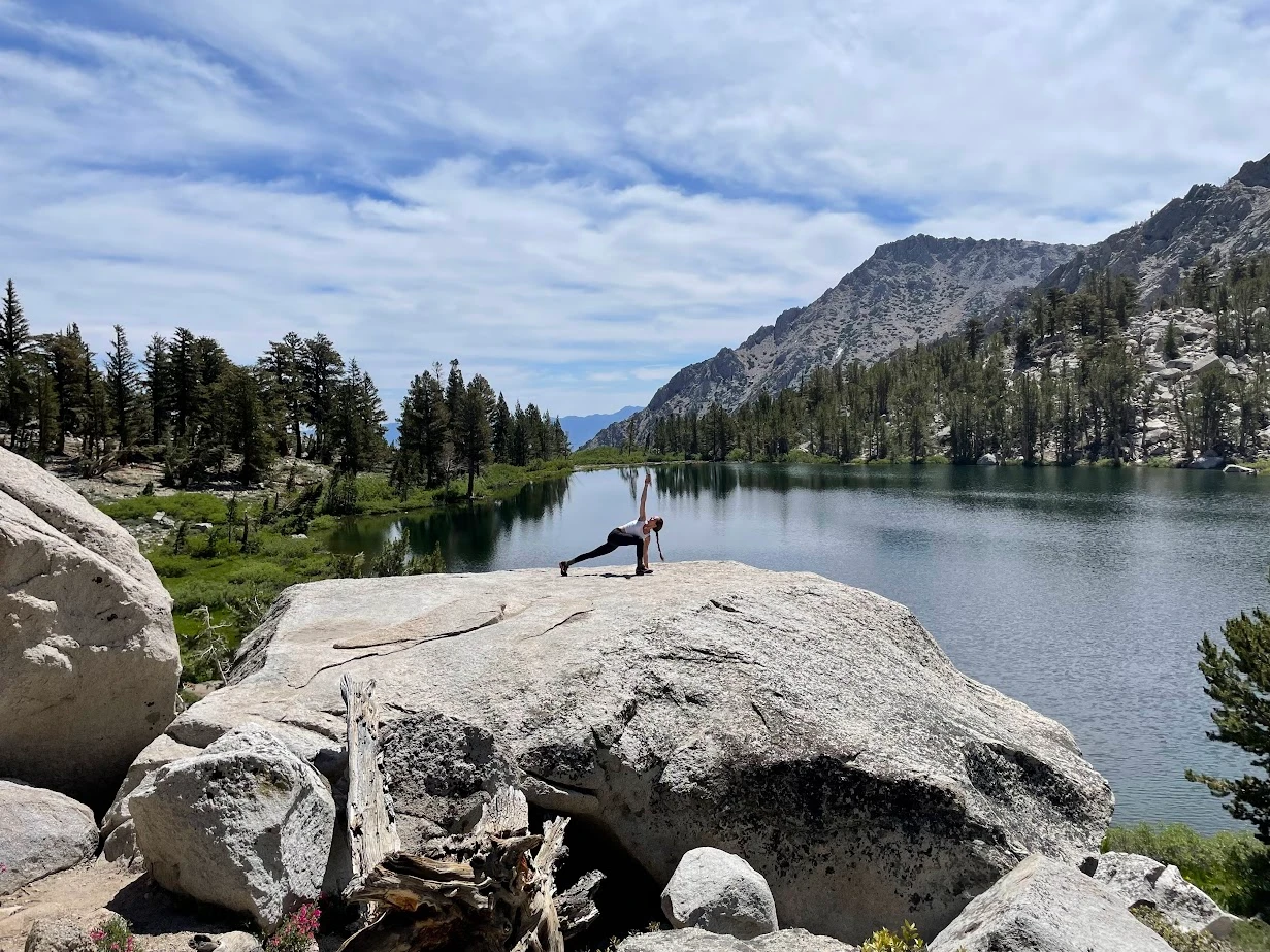 Yoga pose on a rock by a mountain lake